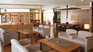 A modern hotel lobby with seating areas, a reception desk, and a bar. - Matsudaya Ryokan (Hanamaki)