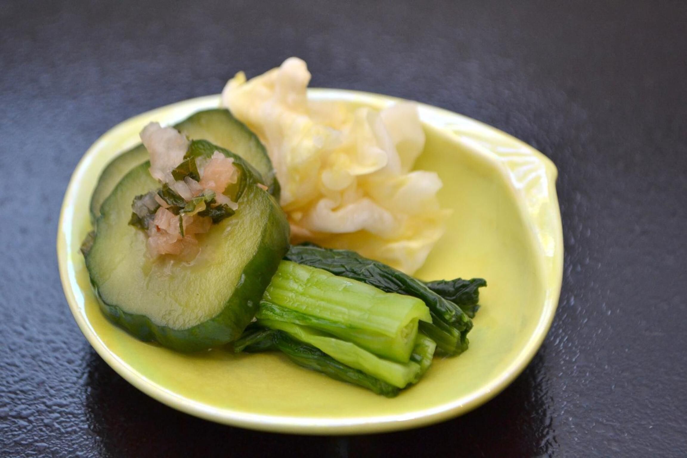 Un plato con pepino en rodajas, camarones y hojas verdes.