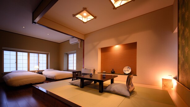 A traditional Japanese-style room with tatami flooring, a low table, cushions, and sliding doors. - Matsudaya Ryokan (Hanamaki)