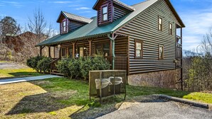 A log cabin with a porch, a small attached structure, and a gravel driveway. - Mountain Views & FREE Attraction Tickets (Gatlinburg)