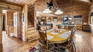 A wooden cabin interior with a dining table, chairs, and a chandelier. - Mountain Views & FREE Attraction Tickets (Gatlinburg)
