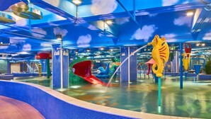 Parque aquático coberto com toboáguas, gerador de ondas e escultura de golfinho.