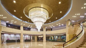 Um hall amplo com um lustre imponente, vários níveis e uma escadaria curva.