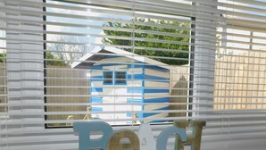A window with horizontal blinds, a small blue and white structure visible through the blinds, and wooden letters spelling "BeCl" on the window sill. - 22 Cliff Road -  stunning, beautifully renovated, contemporary, end terrace cottage (Sheringham)