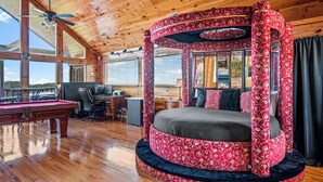 A spacious room with a pool table, a comfortable bed with a canopy, and a desk with a computer.
