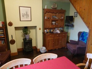 A cozy living room with a wooden cabinet, a fireplace, a television, and a dining area with a red tablecloth.