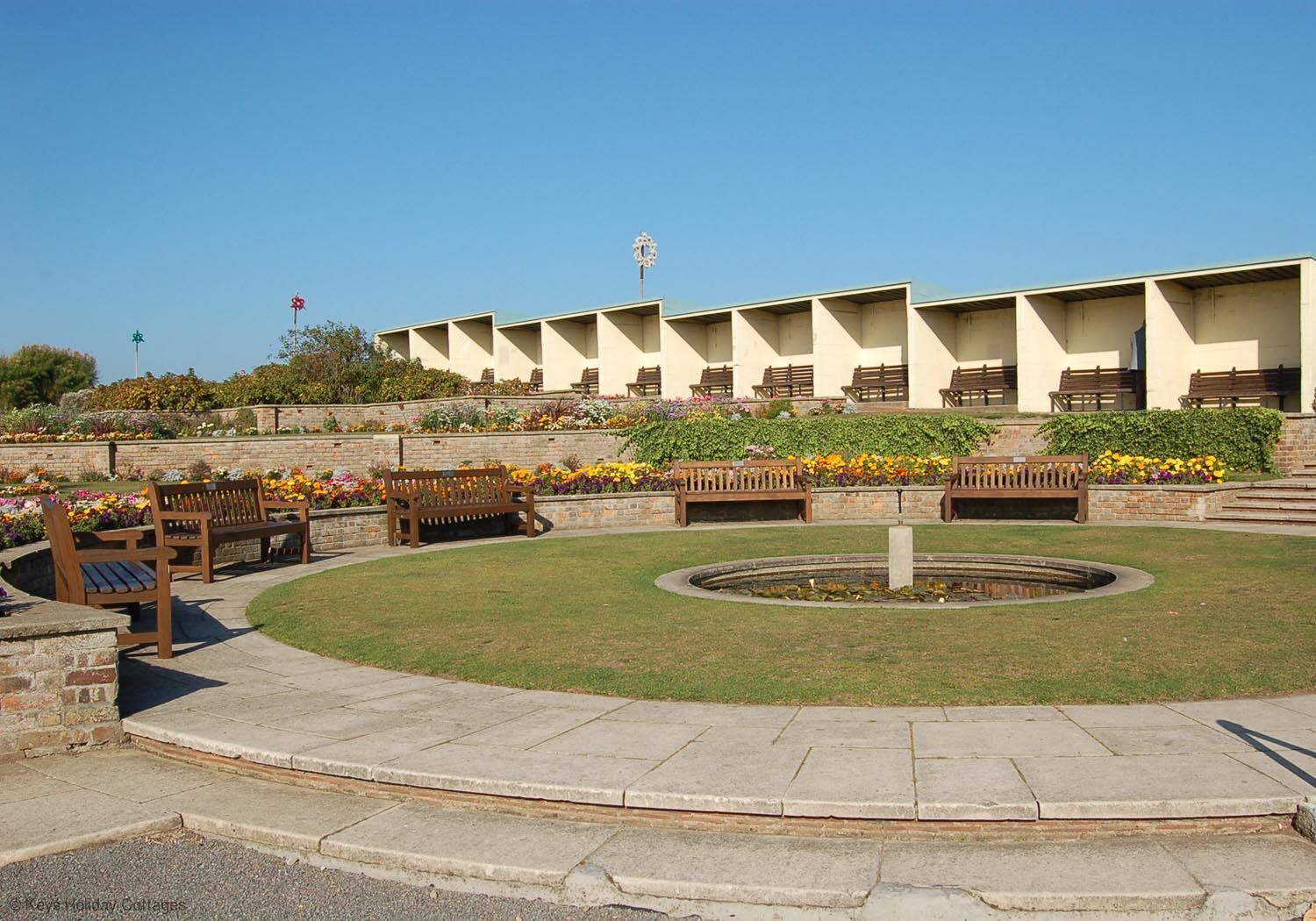 A courtyard with a fountain, benches, and flower beds.
