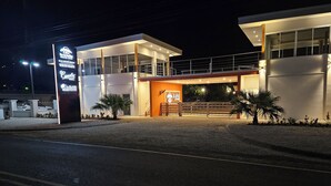 Um edifício moderno com fachada de vidro, entrada destacada e uma placa indicando casa de vidro.