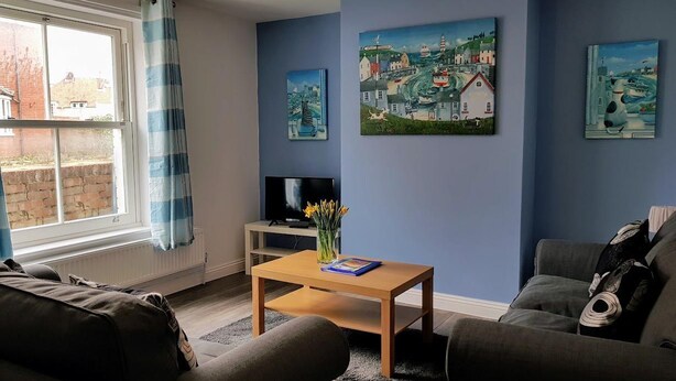 A living room with a sofa, a coffee table, and artwork on the walls. - Westbrook, Regis Place - A delightfully modernised period, former fisherman’s semi-detached cottage (Sheringham)