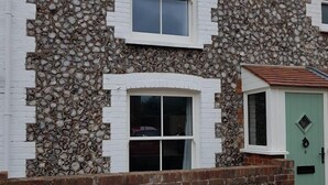 A two-story house with a stone facade, white window frames, and a green door. - Westbrook, Regis Place - A delightfully modernised period, former fisherman’s semi-detached cottage (Sheringham)
