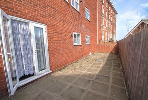 A narrow brick alleyway with a red brick building on one side and a wooden fence on the other.
