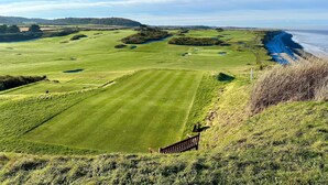 A golf course with a wooden fence, a clear view of the ocean, and a distant hill. - The Prairie -  a deceptively spacious cottage with parking close to the beach in Sheringham (Sheringham)