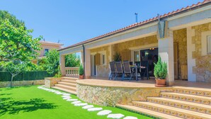 A house with a stone exterior, a covered patio with outdoor furniture, and a well-maintained lawn. - CASA EL CIPRES - Villa with private pool in Sa Ràpita. (Llucmajor)