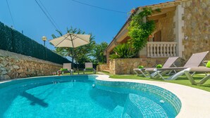 A swimming pool with tiled edges, lounge chairs, and a stone wall. - CASA EL CIPRES - Villa with private pool in Sa Ràpita. (Llucmajor)