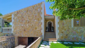 A stone building with a stone staircase leading to a door, a small outdoor seating area, and a paved pathway with stepping stones. - CASA EL CIPRES - Villa with private pool in Sa Ràpita. (Llucmajor)