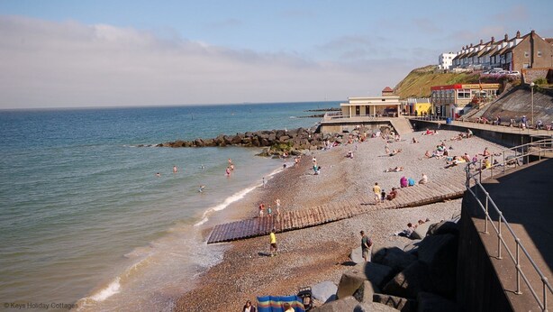 A beach with a rocky shoreline, a pier, and buildings in the background. - In a quiet street this pretty bungalow is located close to the beach & the town centre of Sheringham (Sheringham)