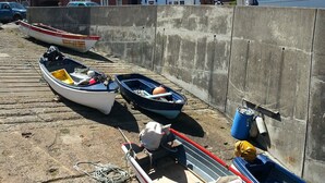A row of boats lined up against a concrete wall with houses in the background. - In a quiet street this pretty bungalow is located close to the beach & the town centre of Sheringham (Sheringham)