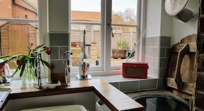 A kitchen with a window, a sink, a red radio, and a plant.