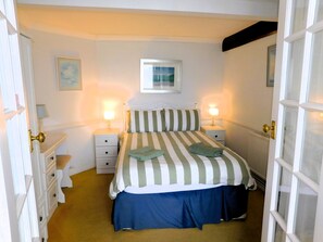 Ein Schlafzimmer mit einem Bett, zwei Nachttischen, einem Heizkörper und einer Tür.