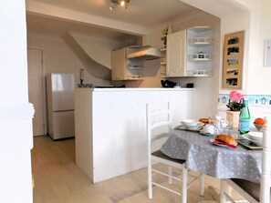A compact kitchen with white cabinets, a built-in oven, and a dining area with a table set for two.