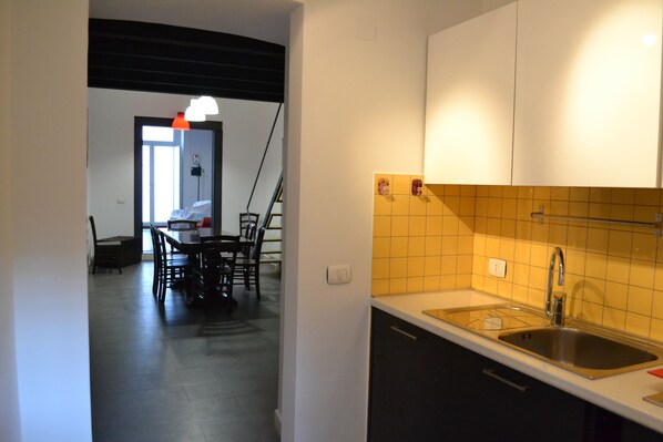 A modern kitchen with a sink, cabinets, and a dining area with chairs and a table. - Loft in the center of Catania for 2 + 2 people (Catania)