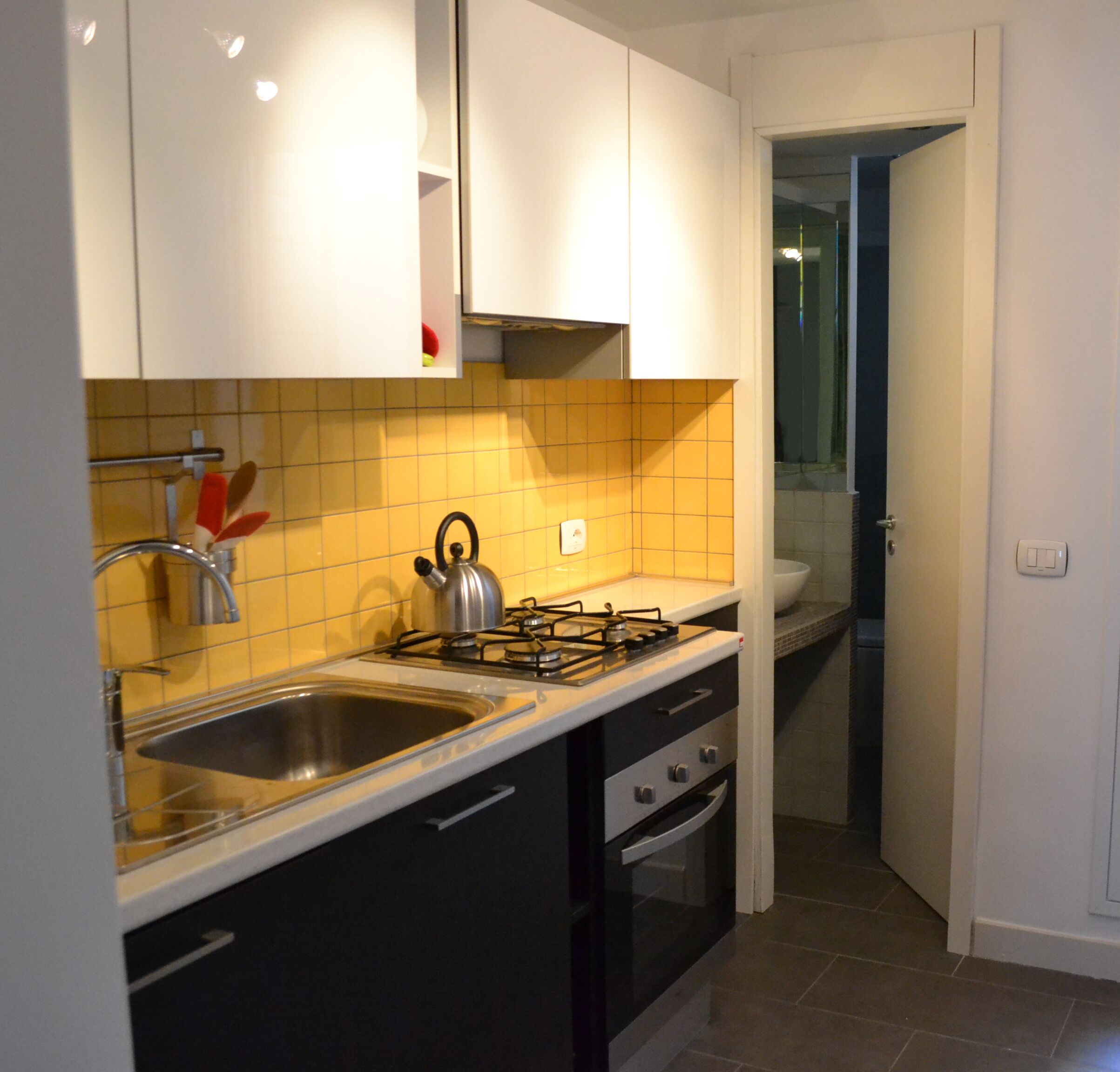 A modern kitchen with a gas stove, double sink, and black cabinets.