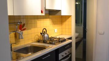 A modern kitchen with a gas stove, double sink, and black cabinets.