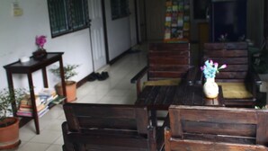 A room with wooden furniture, including a table and chairs, and a bookshelf with books and decorative items. - Ampawan Guesthouse (Chiang Mai)