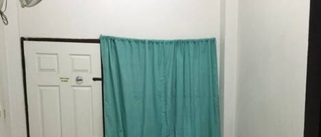 Ein kleines, sauberes Zimmer mit Bett, Schreibtisch, Stuhl und Tür.