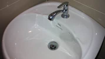 A white bathroom sink with a chrome faucet and a drain.