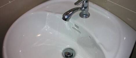 A white bathroom sink with a chrome faucet and a drain.