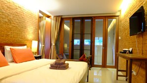 A hotel room with a large bed, a flat-screen TV mounted on the wall, and a sliding glass door leading to a balcony. - The White Elephant Home (Chiang Mai)
