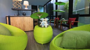 A modern living room with green textured sofas, a wooden coffee table with a decorative elephant figurine, and a kitchen area with a bar and pendant lights. - The White Elephant Home (Chiang Mai)