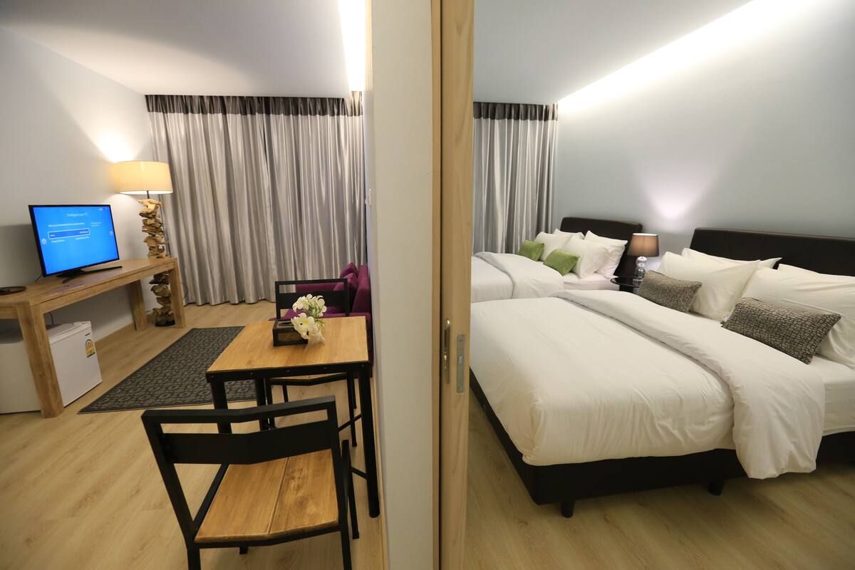 A hotel room with a desk, computer, and a bed with white bedding.