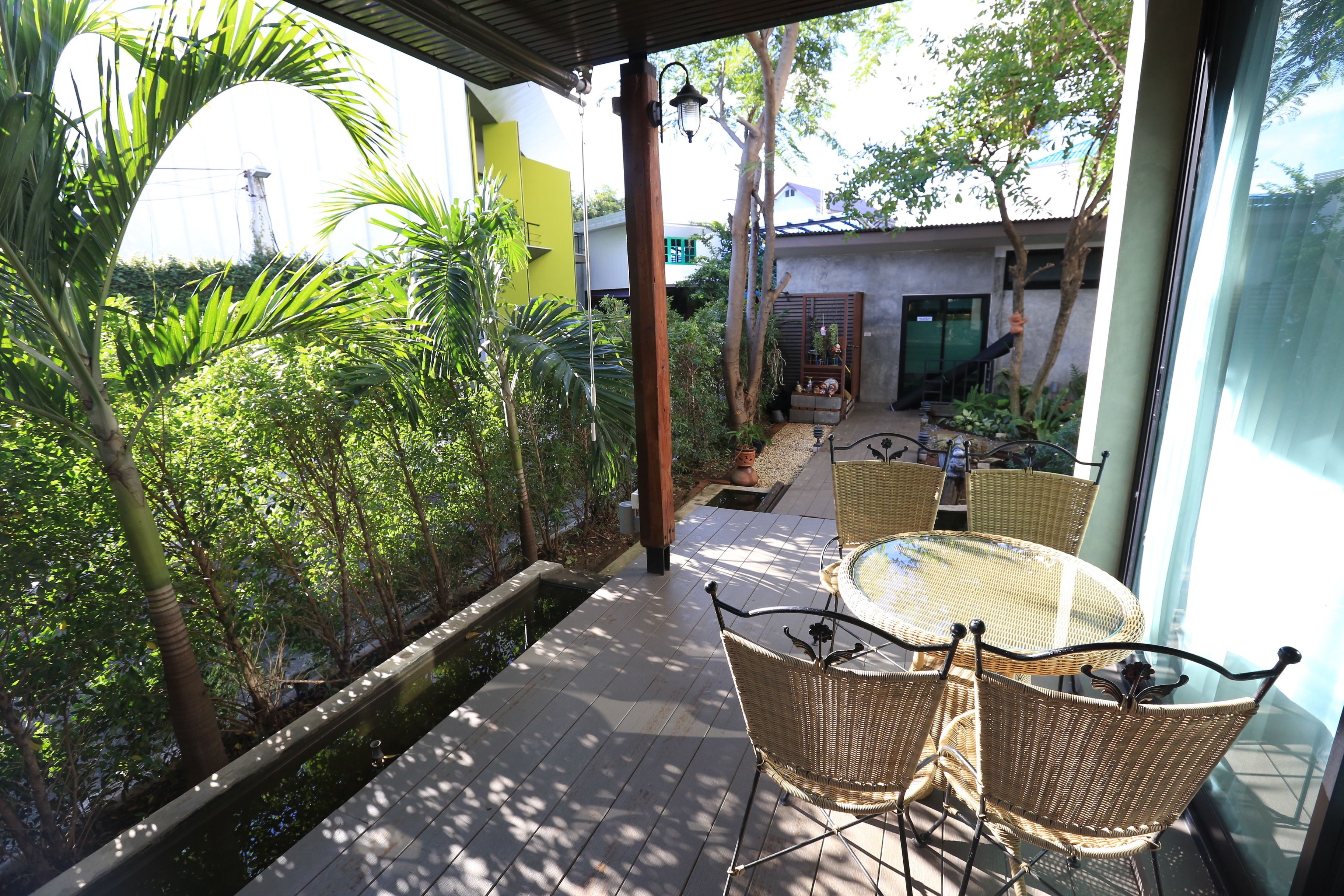 A patio with wicker furniture, a small water feature, and lush greenery.