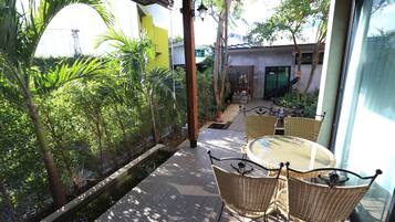 A patio with wicker furniture, a small water feature, and lush greenery.