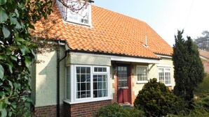 A two-story house with a red-tiled roof, a brick facade, and a small front garden. - Walma has become a firm favourite with holidaymakers , a perfect retreat for family and friends. (Cromer)