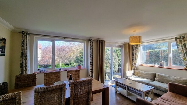 A spacious living room with a dining area, large windows, and a sofa. - Walma has become a firm favourite with holidaymakers , a perfect retreat for family and friends. (Cromer)