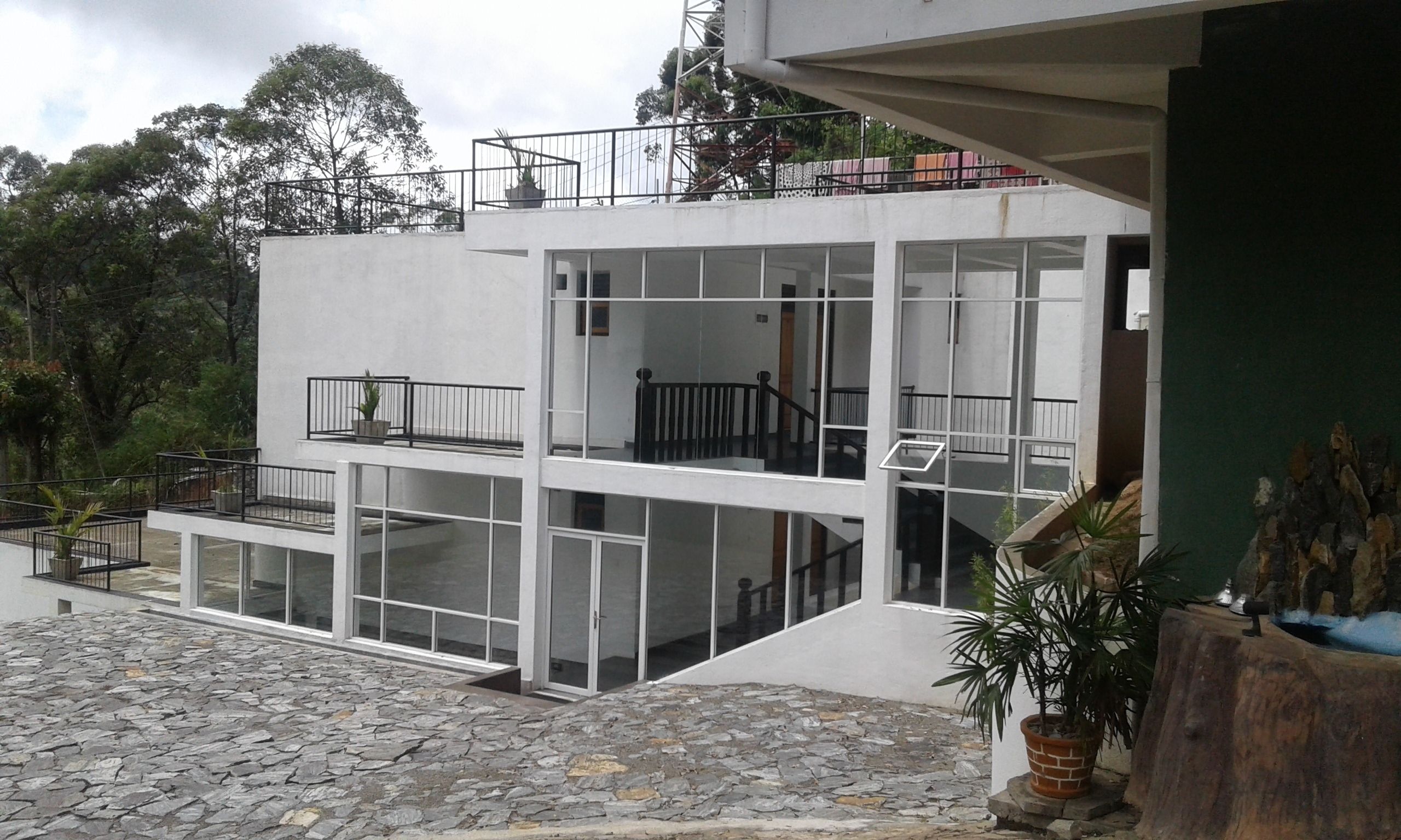 A modern multi-story building with balconies, large windows, and a stone-paved courtyard.