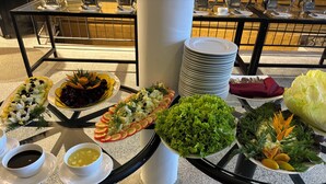 A buffet table with various dishes, including salads, fruits, and vegetables, and a stack of white plates. - Hotel Alta Vista (Ella)