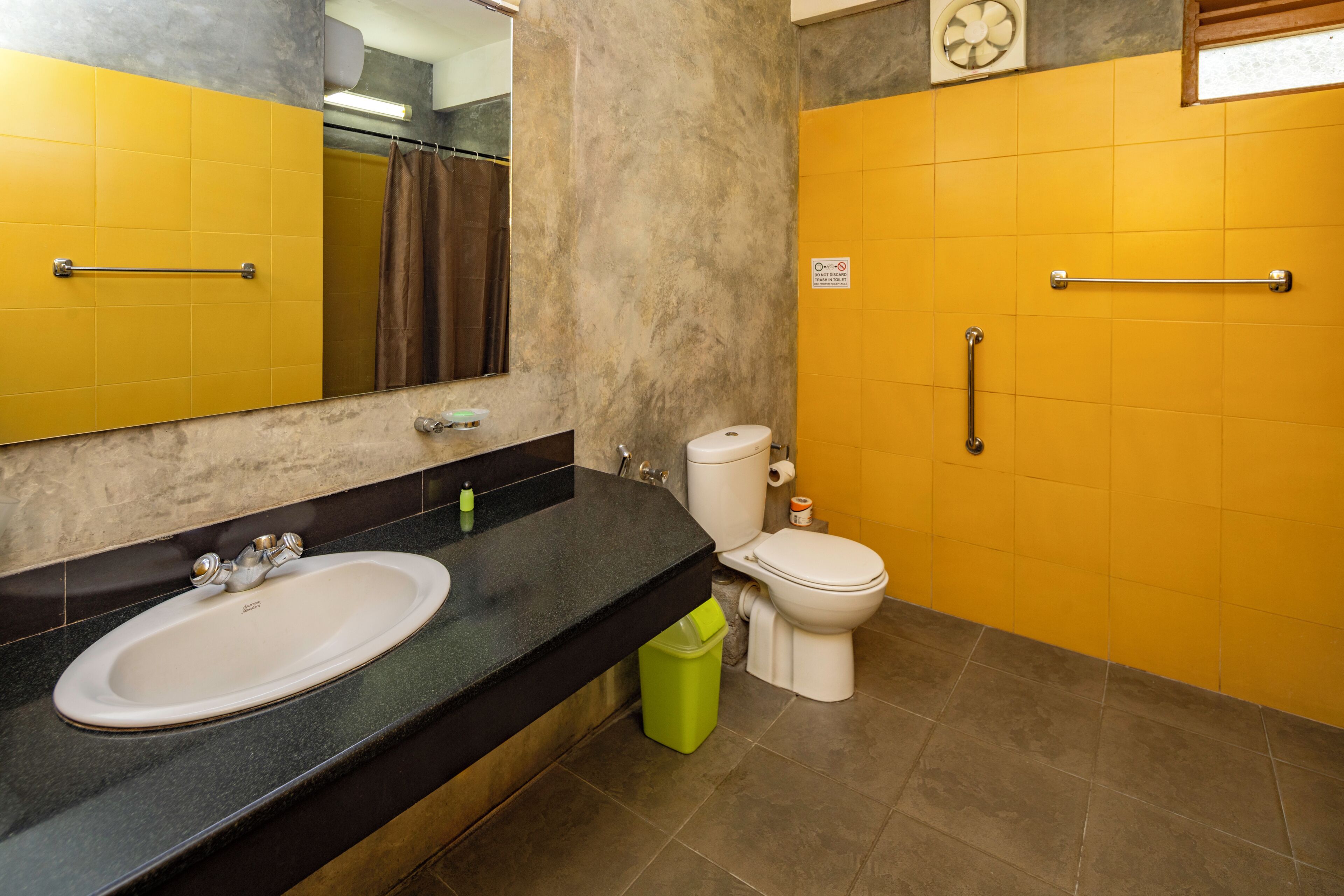 A bathroom with a sink, toilet, and handrails.