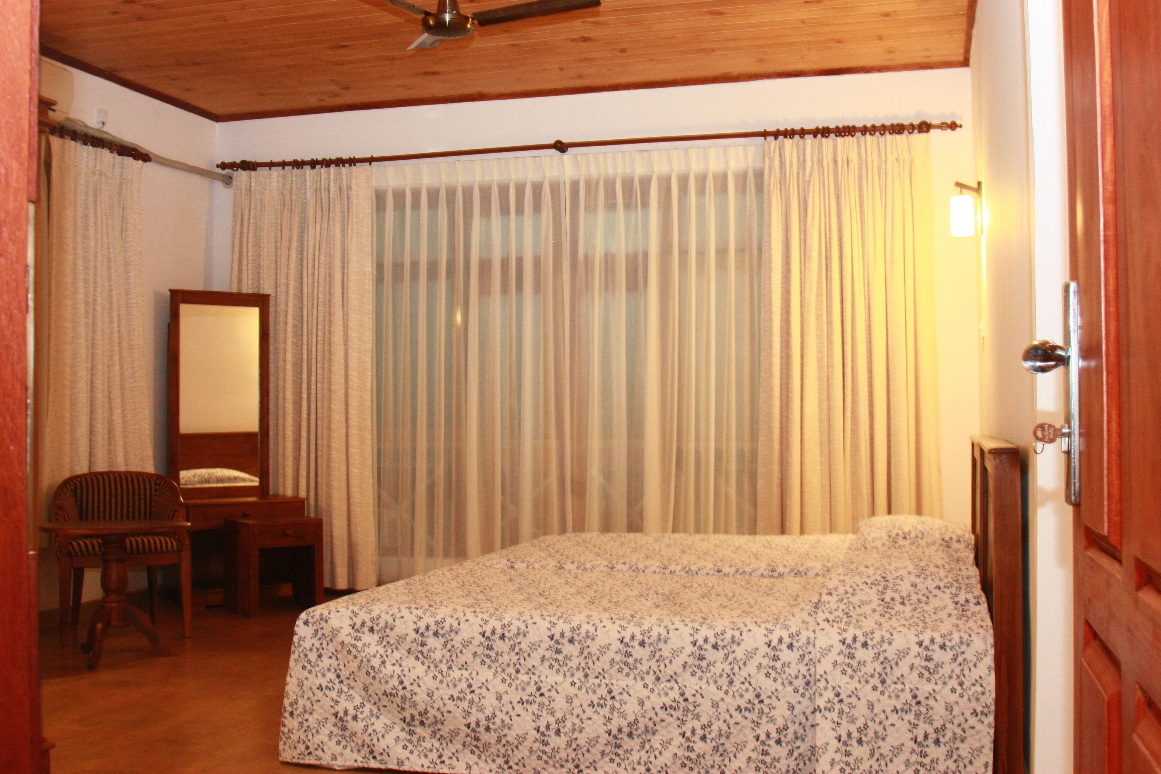 Un dormitorio con cama, una silla, un escritorio y un espejo.
