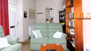 Ein Wohnzimmer mit einem grünen Sofa, einem Holzregal und einem roten Vorhang.