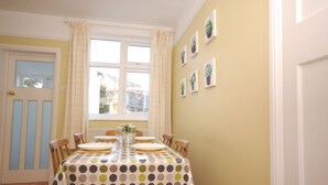 A dining room with a table set for four, a window with curtains, and potted plants on the wall. - This delightful semi-detached cottage is close to walks,  bird watching & minutes from the beach. (Sheringham)