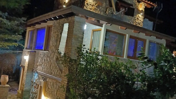 A stone building with a tiled roof, illuminated windows, and a stone pathway leading to the entrance. - Family Abode for Vacation in Arachova (Distomo-Arachova-Antikyra)