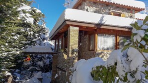 A snow-covered building with a stone facade, wooden balcony, and a clear blue sky. - Family Abode for Vacation in Arachova (Distomo-Arachova-Antikyra)