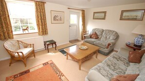 A living room with a sofa, armchair, coffee table, and a rug. - Romany Rye is one of the oldest and prettiest Fisherman's cottage in Sheringham in a great location (Sheringham)