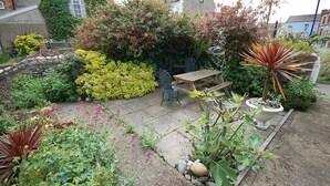 A garden with a wooden bench, potted plants, and a variety of flowers. - Romany Rye is one of the oldest and prettiest Fisherman's cottage in Sheringham in a great location (Sheringham)
