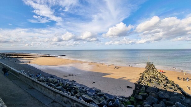 A beach with a rocky breakwater, calm sea, and clear sky. - Romany Rye is one of the oldest and prettiest Fisherman's cottage in Sheringham in a great location (Sheringham)