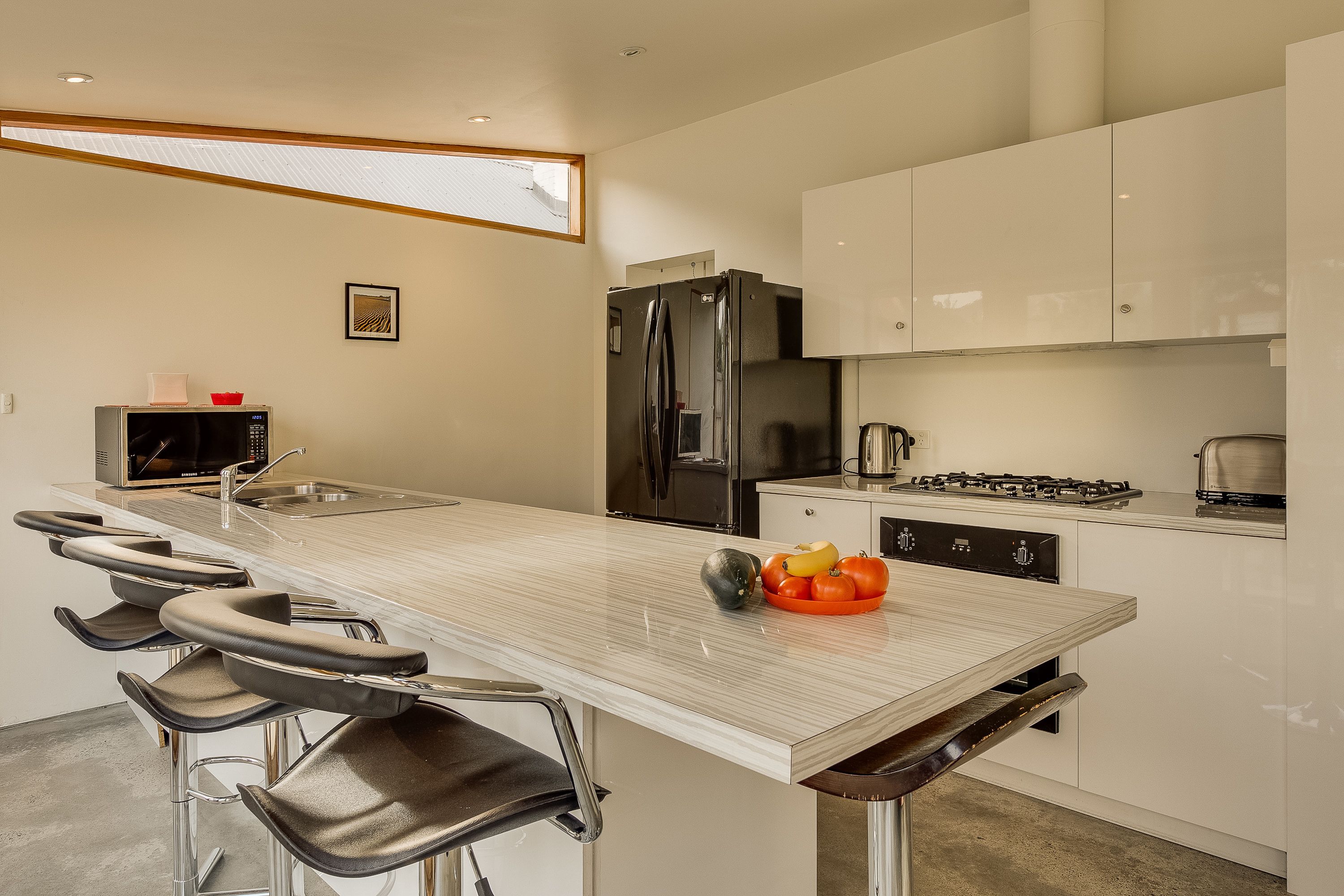 A modern kitchen with a central island, stainless steel appliances, and bar stools.